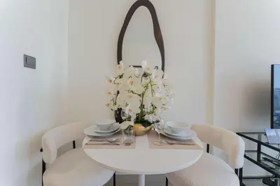 a white dining room table with white chairs and a mirror at TRPS - Azizi Riviera 23, Al Meydan - Contemporary Studio in the Heart of Dubai in Dubai