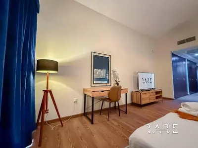 a bedroom with a desk with a lamp and a bed at Rare Holiday Homes - Mediterranean Cluster - Near Metro - Discovery Garden - Building# Med 83 - R105 in Dubai
