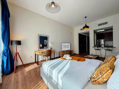 a bedroom with a large bed and a desk at Rare Holiday Homes - Mediterranean Cluster - Near Metro - Discovery Garden - Building# Med 83 - R105 in Dubai