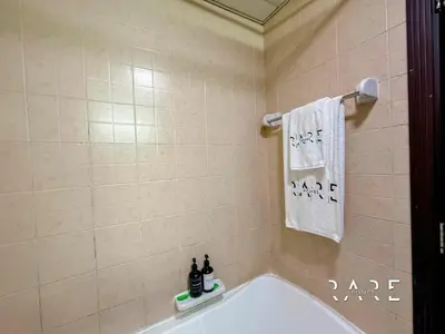a bathroom with a tub and a white towel at Rare Holiday Homes - Mediterranean Cluster - Near Metro - Discovery Garden - Building# Med 83 - R105 in Dubai