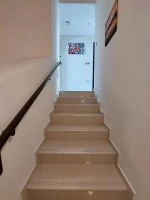 a stairway with white walls and white stairs at Damac Hills 2- Relaxing 3BR townhouse - Homeyvillas in Dubai