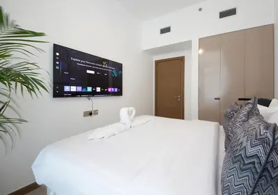a bedroom with a white bed and a flat screen tv at Luxury 2BR in Urban Oasis by Missoni on High Floor in Dubai