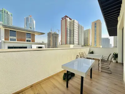 a balcony with tables and chairs on top of a building at Vserve - Peaceful 1 BR Getaway in Vibrant JVC in Dubai