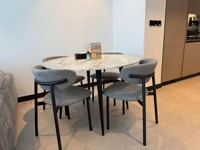 a table with four chairs and a marble table and a refrigerator at Vserve - 1 BR Escape With City Views & Canal Vibes in Dubai