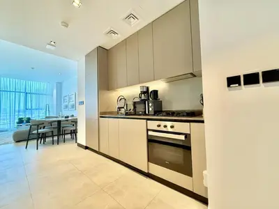 a kitchen with a stove top oven next to a table at Vserve - 1 BR Escape With City Views & Canal Vibes in Dubai