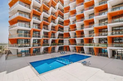 an apartment building with a swimming pool in front of it at Trendy Studio Apartment in Binghatti Crystals in Dubai