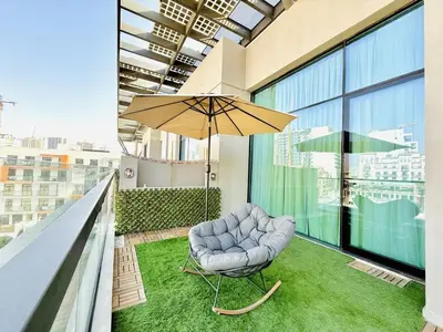 a chair and an umbrella on a balcony at Vserve -Elegant Penthouse Stay in the Heart of JVC in Dubai