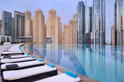 a pool with chaise lounge chairs in front of a city skyline at Stunning One Bedroom in the Marina in Dubai