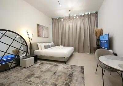a bedroom with a bed and a table and a tv at Chic Studio Apartment Binghatti Canal Business Bay in Dubai