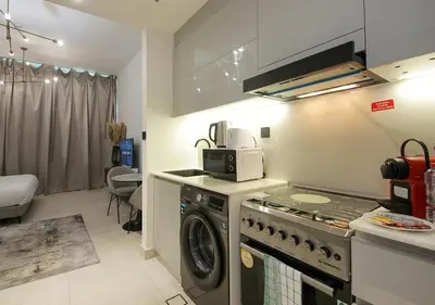 a kitchen with a stove and a washing machine at Chic Studio Apartment Binghatti Canal Business Bay in Dubai