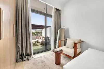 a bedroom with a bed and a window with a patio at Amazing Studio in Azizi Riviera 1 in Dubai