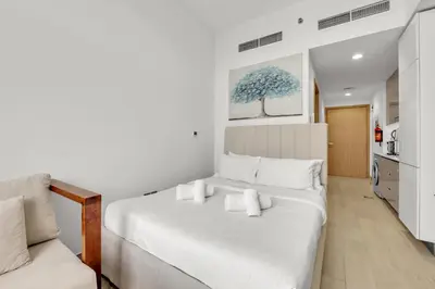 a bedroom with a white bed and a white couch at Amazing Studio in Azizi Riviera 1 in Dubai
