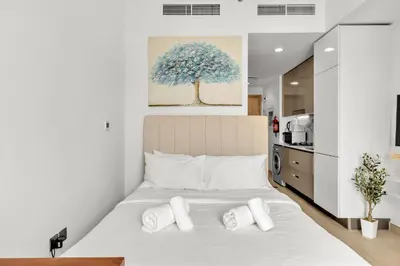 a bedroom with a large bed with a tree painting on the wall at Amazing Studio in Azizi Riviera 1 in Dubai