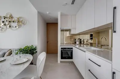 a kitchen with white cabinets and a dining table at ADDRESS Residences by Happy Season in Dubai