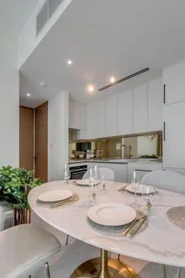 a white kitchen with a table with plates on it at ADDRESS Residences by Happy Season in Dubai