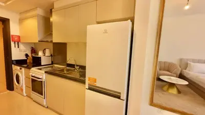 a kitchen with a refrigerator next to a living room at Cosy Studio in Carson Tower C in Dubai