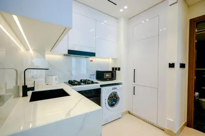 a white kitchen with a washing machine and a washer at Bright 1BR in Binghatti House, Prime Location in Dubai