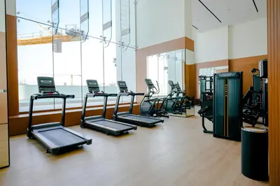 a gym with a row of treadms and elliptical machines at Bright 1BR in Binghatti House, Prime Location in Dubai
