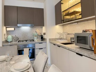 a kitchen with a counter with a table and a microwave at Elegant and Stylish 1BR, Grand Blue in Dubai