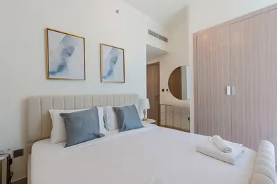 a bedroom with a large white bed with blue pillows at TRPS - Azizi Riviera 23, Al Meydan - 2BR Elegant Apartment with Access to Premium Amenities in Dubai