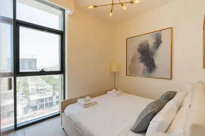 a bedroom with a bed and a large window at TRPS - Azizi Riviera 23, Al Meydan - 2BR Elegant Apartment with Access to Premium Amenities in Dubai