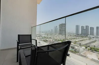 a chair on a balcony with a view of a city at TRPS - Azizi Riviera 23, Al Meydan - 2BR Elegant Apartment with Access to Premium Amenities in Dubai