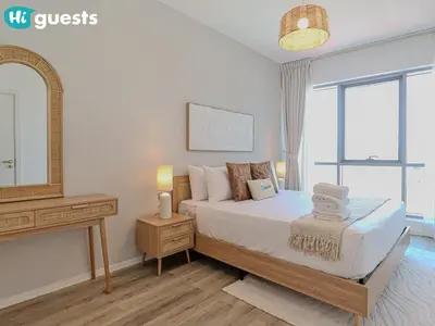 a bedroom with a bed and a dresser and a mirror at HiGuests - Luxe 2BR Overlooking Golf Course & Greenery in Dubai