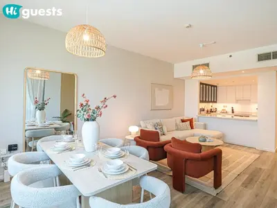 a living room with a couch and a table and chairs at HiGuests - Luxe 2BR Overlooking Golf Course & Greenery in Dubai
