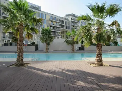 a pool with palm trees in front of a building at Frank Porter - Midtown By Deyaar - Dania 2 in Dubai