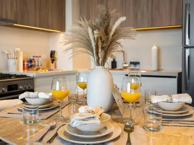 a table with plates and wine glasses and a vase at Contemporary Parkfront 2BR Dubai Hills Living in Dubai