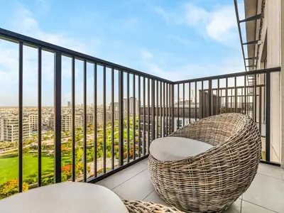 a balcony with a rattan chair and a view at Contemporary Parkfront 2BR Dubai Hills Living in Dubai