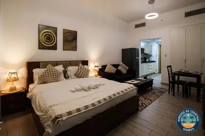 a bedroom with a large bed and a living room at Modern Studio Fully Furnished Oxford Residence in Dubai