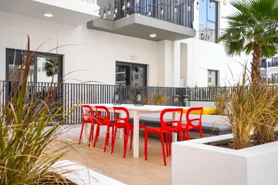 a white table and red chairs on a deck at YouCo Dubai apart-hotel in Dubai