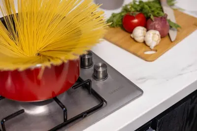 a red pot on a stove with vegetables on a counter at New 1BR with Full Balcony Gym Pool and Sauna in Dubai