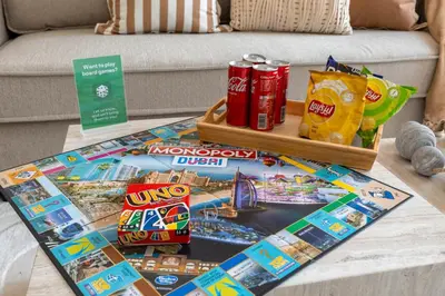 a table with a board game and drinks and snacks at New 1BR with Full Balcony Gym Pool and Sauna in Dubai