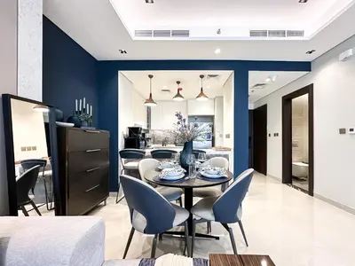 a dining room with blue walls and a table and chairs at Trophy-Luxe Living in a Blue-Hued Haven in Dubai