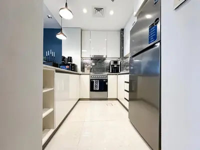 a kitchen with white cabinets and a refrigerator at Trophy-Luxe Living in a Blue-Hued Haven in Dubai