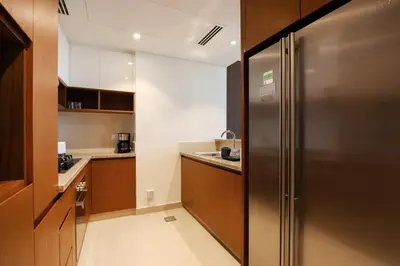 a small kitchen with a stainless steel refrigerator at Livbnb Creekfront 2BR with Skyline Views Steps to Creek Marina in Dubai