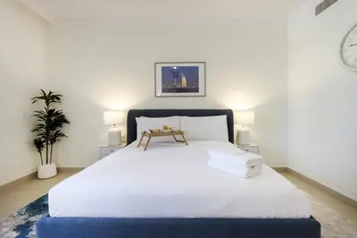 a bedroom with a large white bed with two lamps at Livbnb Creekfront 2BR with Skyline Views Steps to Creek Marina in Dubai