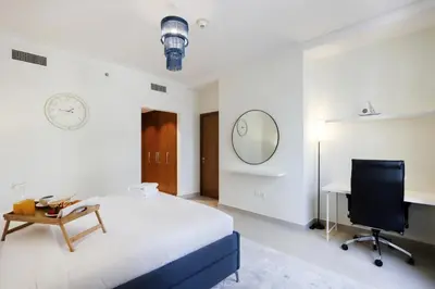 a bedroom with a bed and a desk and a chair at Livbnb Creekfront 2BR with Skyline Views Steps to Creek Marina in Dubai