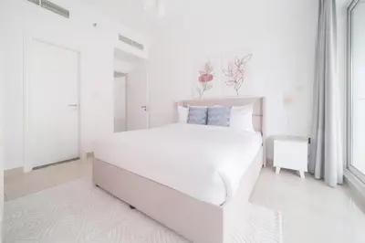 a white bedroom with a white bed and a window at Stella Stays Barsha Heights in Dubai