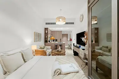 a bedroom with a white bed and a living room at FIRST CLASS Studio Contemporary Living in JVT in Dubai