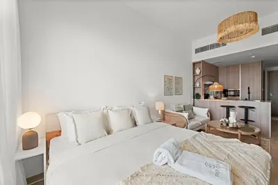 a bedroom with a large white bed and a living room at FIRST CLASS Studio Contemporary Living in JVT in Dubai
