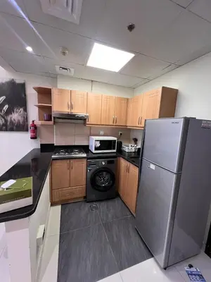 a kitchen with a stainless steel refrigerator and wooden cabinets at Stylish 1BR in Elite 7 Sports City in Dubai