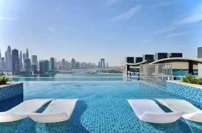 a swimming pool with two chairs and a city skyline at FIRST CLASS Studio Palm Paradise in Dubai