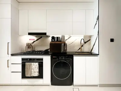 a white kitchen with a washing machine in it at Luxe Living in the Heart of Bbay w Jacuzzi in Dubai