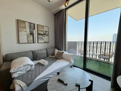 a living room with a couch and a large window at Stylish Studio in JVC with Pool, Gym, Balcony & Modern Comforts in Dubai