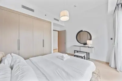 a white bedroom with a bed and a desk at Act tower-1BR near Burj Khalifa in Dubai