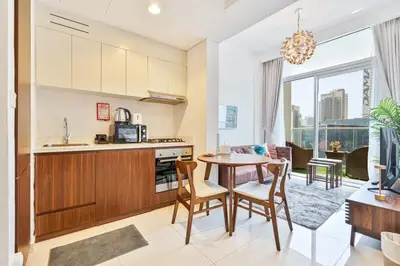 a kitchen and living room with a table and chairs at Modern 1 Bed with Burj View From Balcony & Pool and Gym Access in Dubai