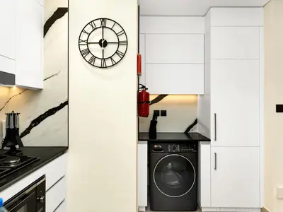 a kitchen with a washing machine and a clock at Exclusive 1BD with Burj View & Private Jacuzzi in Dubai